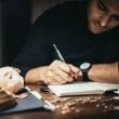 focused man writing in account book at table