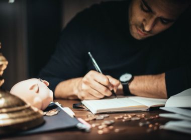 focused man writing in account book at table